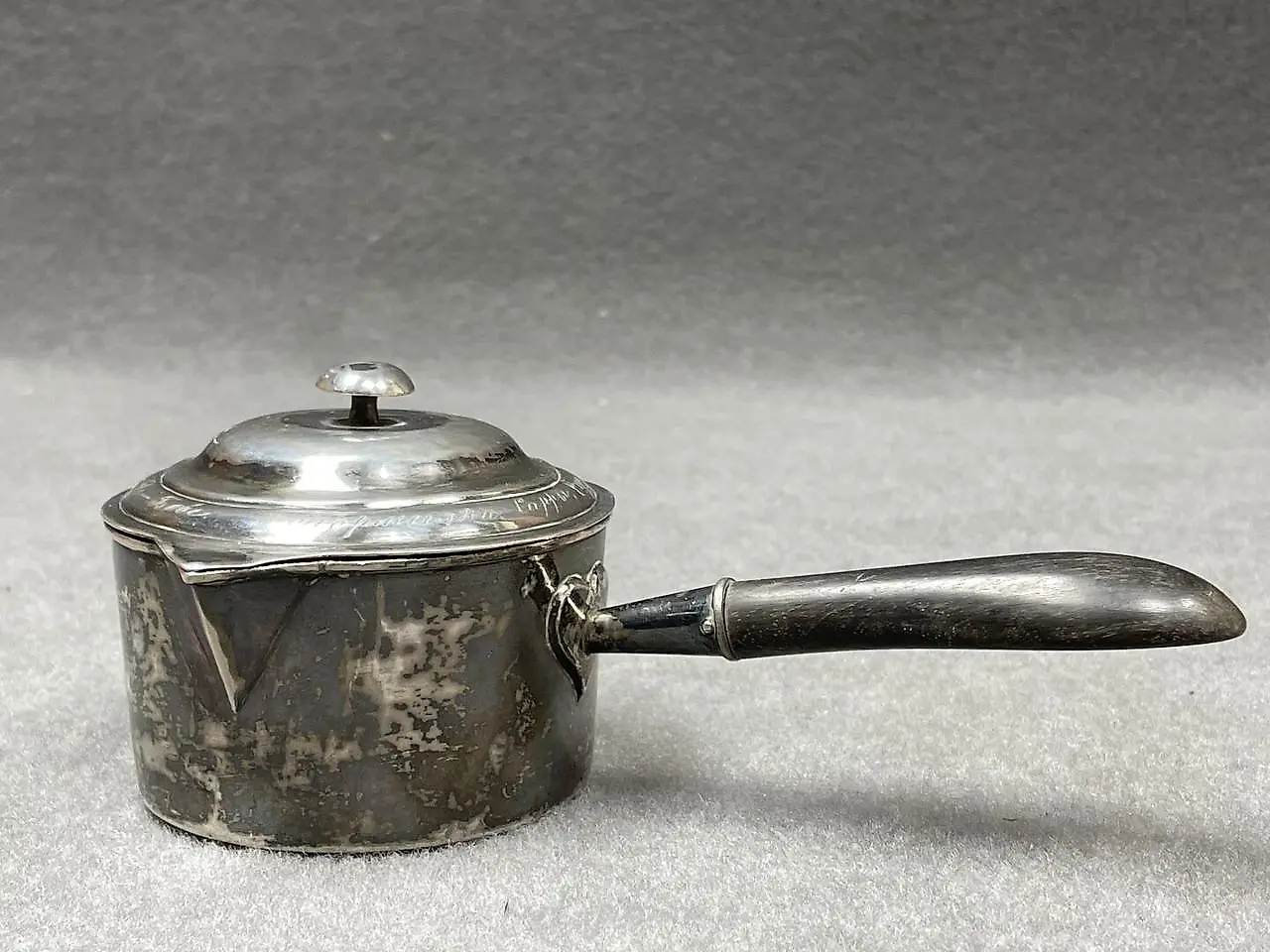 Silver ladle with a wooden handle that has been blackened. Marks...