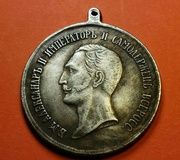 Серебряная медаль Российской империи с портретом русского царя Александра II слева.